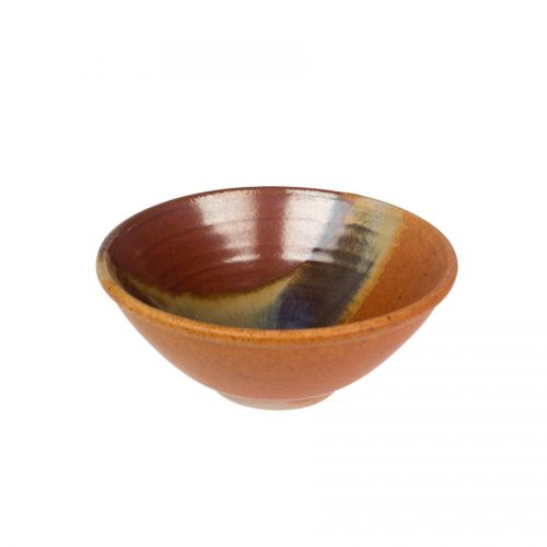 a petite, handmade, red and sandy brown dinnerware bowl with flared sides and a variegated blue band across the surface.